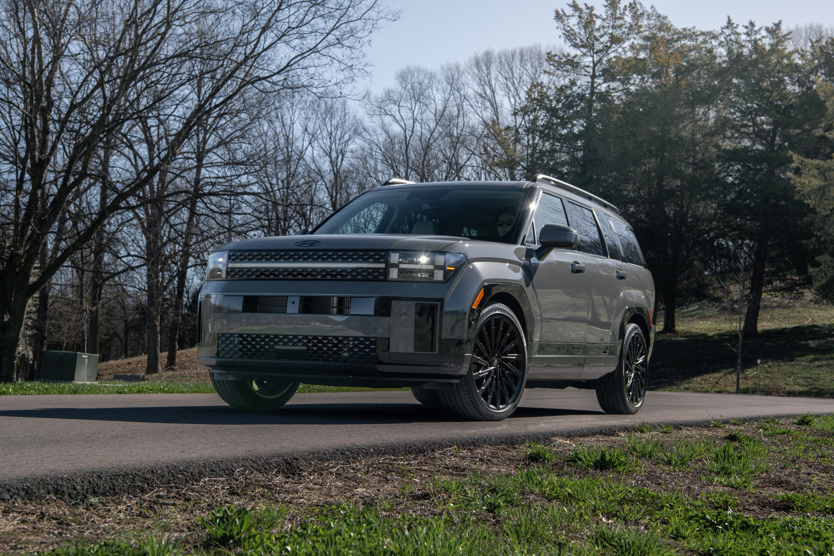 Gray 2027 Hyundai Santa Fe parked on a tree-lined road, front three-quarter view